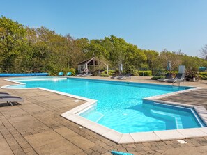 A rectangular swimming pool with a tiled edge, surrounded by lounge chairs and a covered pavilion. - 38 at the Sanctuary Lodges - UK50850 (Rhosfawr, near Pwllheli)