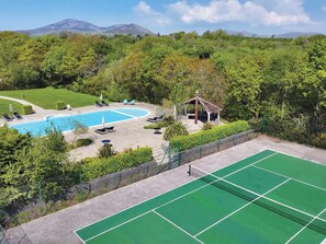 Un campo da tennis, due piscine e un gazebo immersi nel verde.