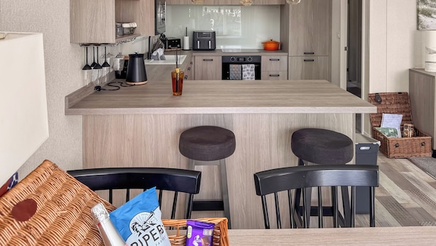 Una cucina moderna con isola centrale, sgabelli da bar e tavolo da pranzo.