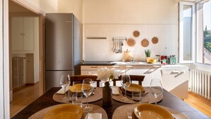 Een moderne keuken met een eethoek voor zes personen, inclusief een centraal kookeiland, een koelkast en een raam met uitzicht.