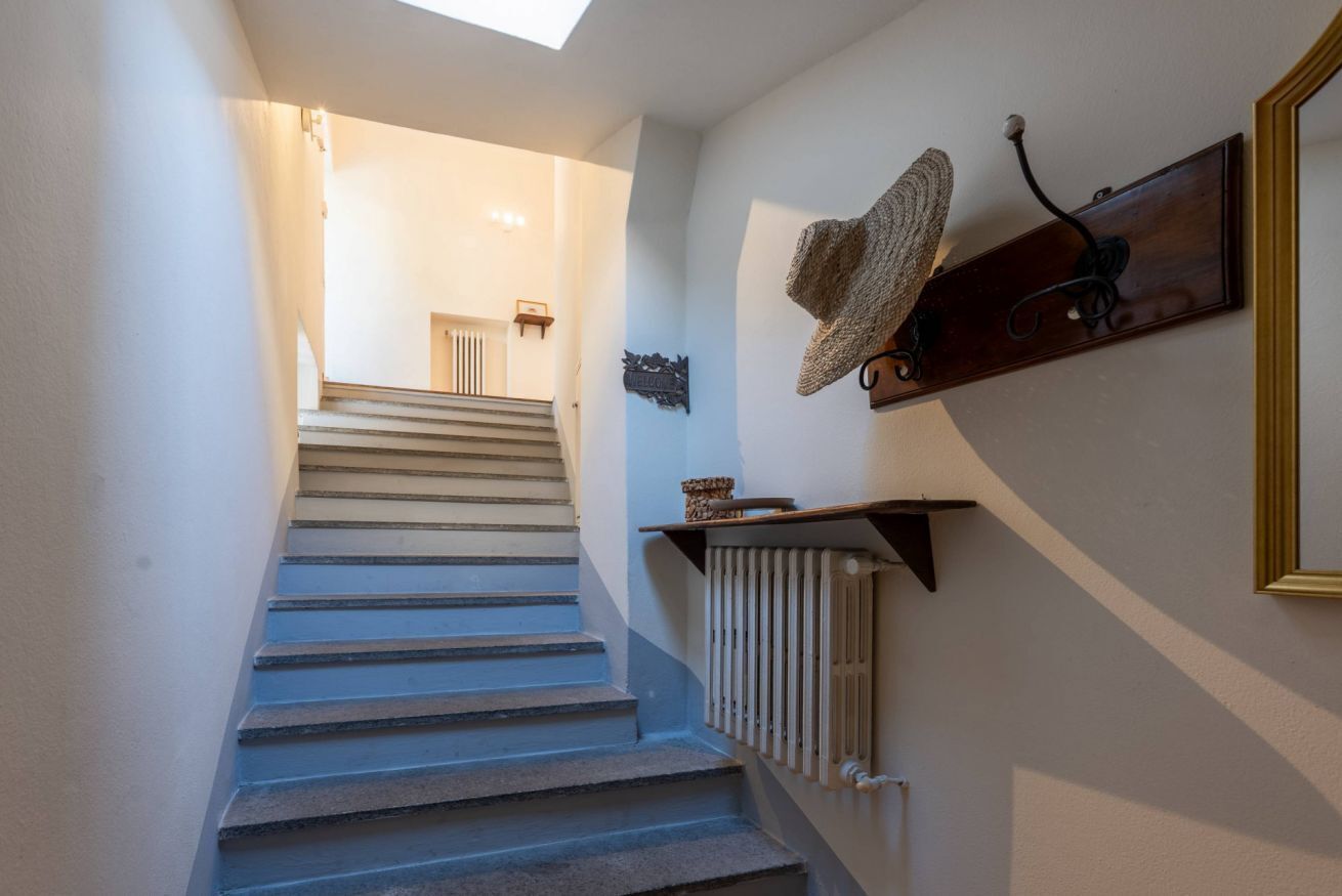 Eine Treppe führt zu einer Zwischenebene mit einem Heizkörper, einem Hut auf einem Wandregal und einem gerahmten Spiegel.