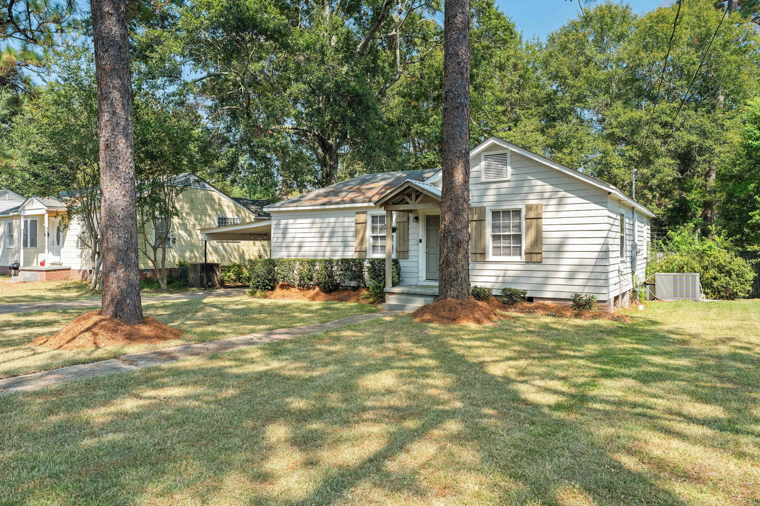 A single-story house with a front porch, surrounded by trees and a well-maintained lawn.