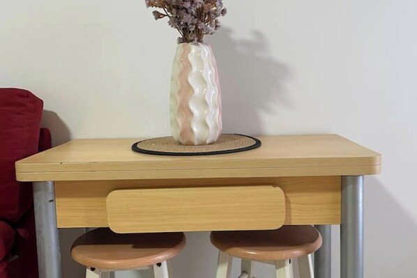 Een klein houten tafeltje met een vaas gedroogde bloemen erop.