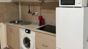 Une cuisine compacte équipée d’un lave-linge, d’un four à micro-ondes et d’un évier.
