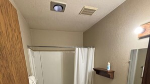 Un baño con ducha, inodoro, lavabo y espejo.