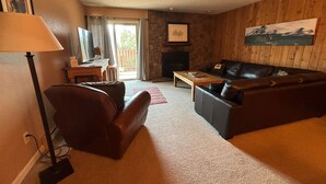 Una sala de estar con un sofá de cuero, una mesa de centro de madera, una televisión y una chimenea.