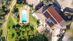 Oversigtsbillede af en bolig med swimmingpool, overdækket terrasse og en indhegnet have.