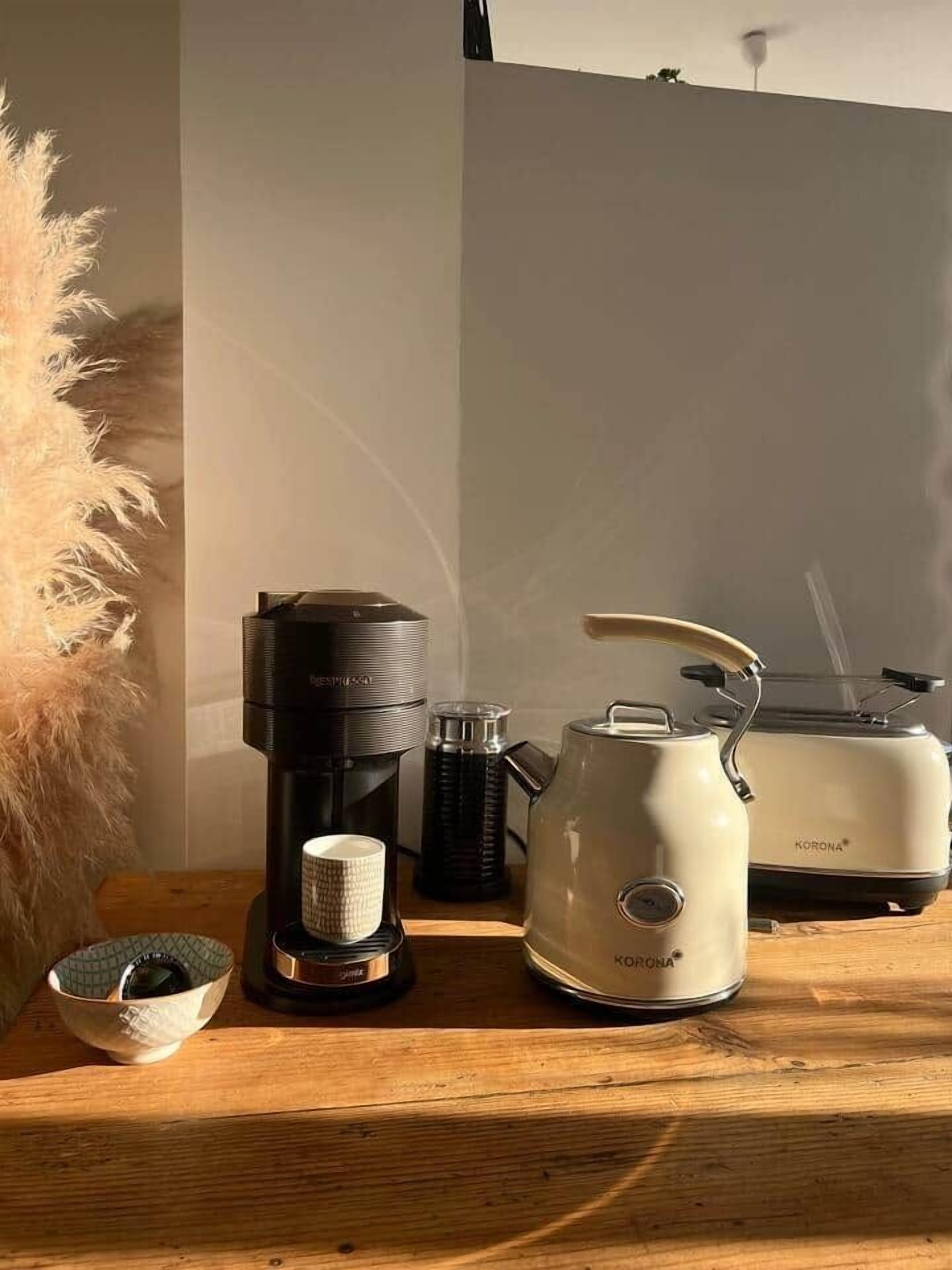 A kitchen counter with a coffee maker, a kettle, a toaster, and a small bowl.