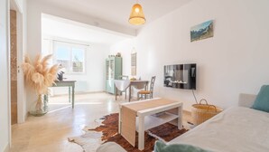 Un vaste espace de vie comprenant une table à manger, un canapé et un téléviseur fixé au mur.