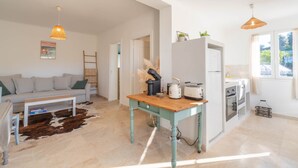 Un grand espace de vie comprenant un canapé, une table basse et un coin cuisine équipé d’une table, d’un grille-pain et d’un réfrigérateur.