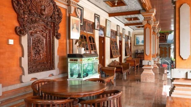 A spacious room with a wooden dining table and chairs, a fish tank, and a series of framed pictures on the walls. - Ceria Guesthouse Seminyak Mitra RedDoorz (Bali)