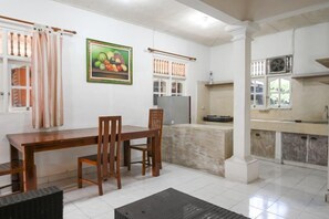 Un comedor con una mesa y sillas de madera, una cocina con armarios y un piso de baldosas.