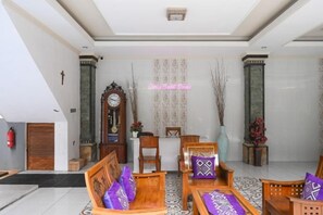 A lobby with a reception desk, seating area, and a clock. - Ceria Guesthouse Seminyak Mitra RedDoorz (Bali)