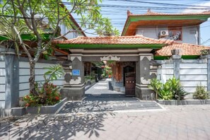 A traditional Indonesian gate with a tiled roof, leading to a building with a red and green facade. - Ceria Guesthouse Seminyak Mitra RedDoorz (Bali)