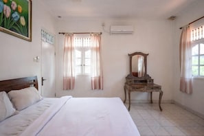 Une chambre à coucher avec un lit, une commode, un miroir et une fenêtre avec des rideaux.