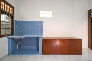 A bathroom with a blue-tiled sink, a wooden cabinet, and a window with bars. - Ceria Guesthouse Seminyak Mitra RedDoorz (Bali)