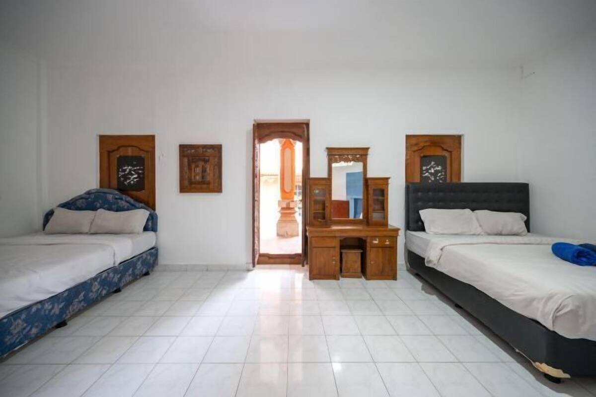 A room with two beds, a wooden desk, and a mirror.