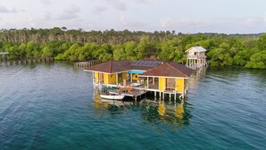 A floating house with a deck, a boat, and a small tower. - Feel right at home in paradise in the eco friendly, off-grid home on Isla Colon. (Isla Colon)