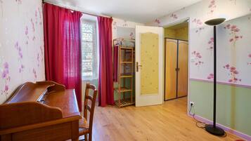 A room with a wooden desk, chairs, a wardrobe, and a floor lamp.