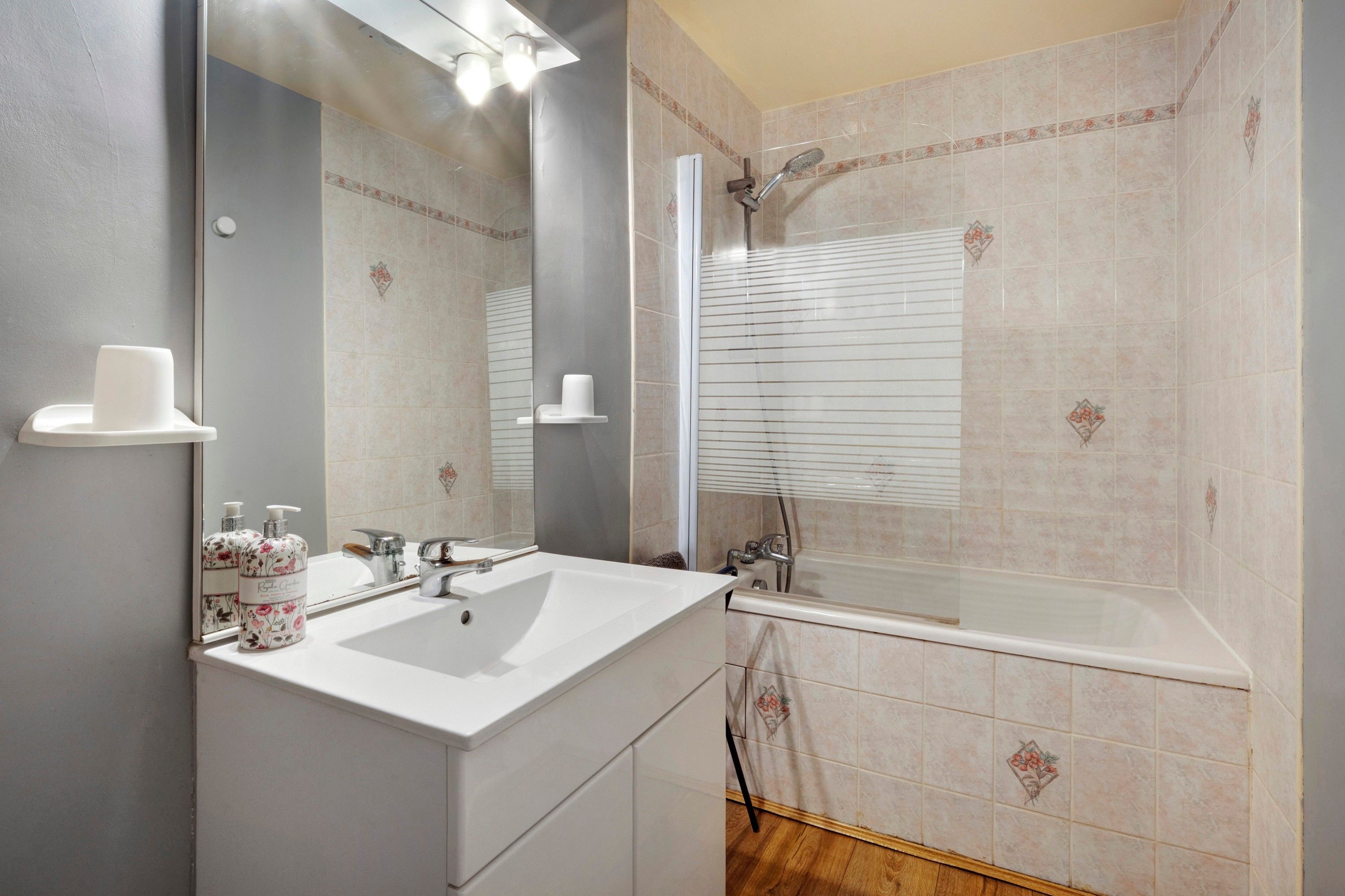 Une salle de bain avec un lavabo blanc, un miroir, une douche et des toilettes.