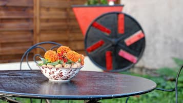 Een ronde metalen tafel met een schaal bloemen en walnoten erop.