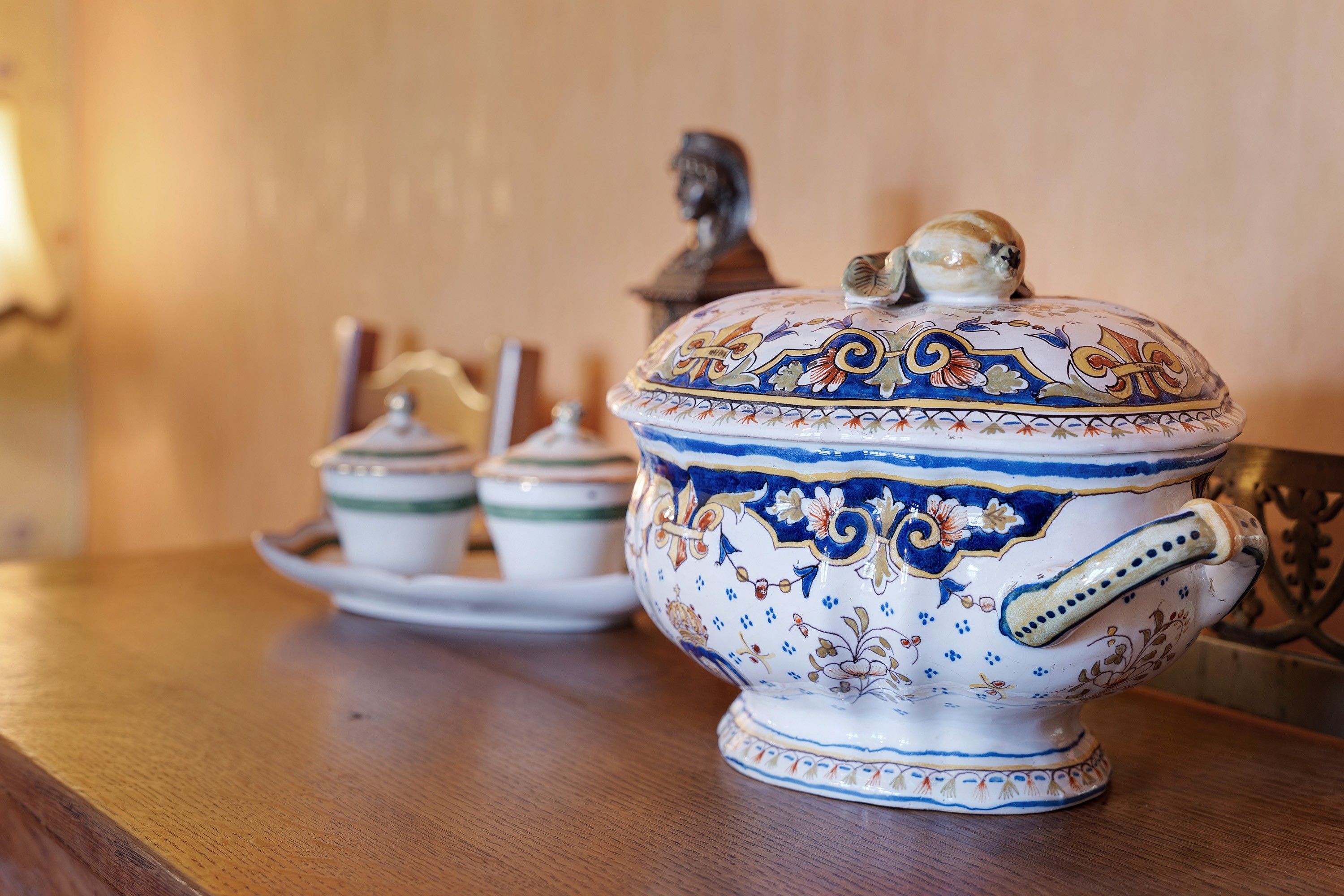 A table with a decorative ceramic tureen and two smaller containers.