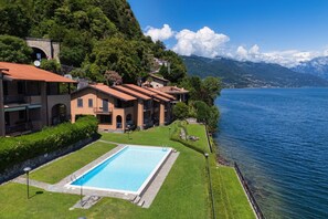 Ein Hotel mit Schwimmbad, Seeblick und Gebäuden mit roten Ziegeldächern.