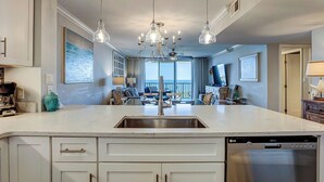 A kitchen with a central island, stainless steel appliances, pendant lighting, and a view to a balcony. - Sunset Rentals | Island Club 2403 (Hilton Head Island)