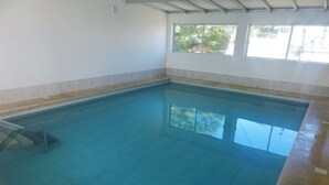 A large indoor swimming pool with clear blue water, tiled walls, and a window providing natural light. - HOTEL CENTENARIO (Atlántida)