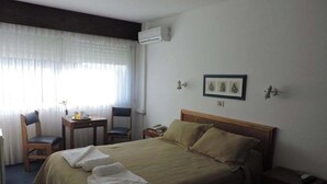 A hotel room with a bed, two chairs, a small table, and a nightstand. - HOTEL CENTENARIO (Atlántida)