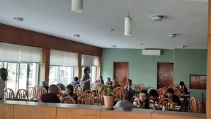 A restaurant with wooden chairs and tables, large windows, and a green wall. - HOTEL CENTENARIO (Atlántida)