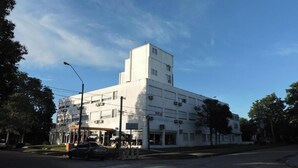 A multi-story building with a flat roof, several air conditioning units, and a parking lot with a few cars. - HOTEL CENTENARIO (Atlántida)