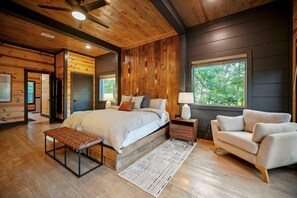 Un dormitorio amplio con una cama grande, un banco, un sofá y una mesita de noche.
