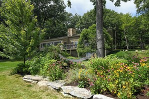 A modern house surrounded by lush greenery and a hammock in the garden. - Spacious 7-Bedroom Lakeside Retreat on Little Sebago Lake (Raymond)