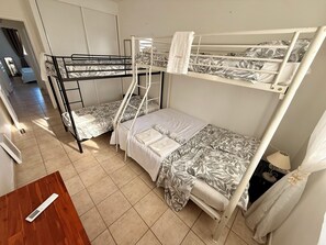 A dormitory room with bunk beds, a wooden table, and a lamp. - 3-Bedroom Apartment by the Sea in Saint François (Saint-François)