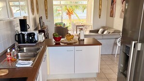 Eine moderne Küche mit Kochinsel, Edelstahlgeräten und einer Essecke mit Sofa und Tisch.