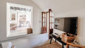 A spacious room with a large window, a flat-screen TV, a wooden bench, and a wicker basket. - Casa Mina - MyHomeinComo (Menaggio)