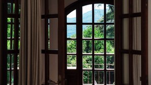 A room with a large arched window offering a view of greenery and mountains. - Casa Mina - MyHomeinComo (Menaggio)