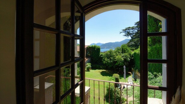 An arched window with a view of a lush garden and mountains. - Casa Mina - MyHomeinComo (Menaggio)