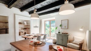 A kitchen with wooden countertops, a dining table set for two, and a view of the outdoors through a large window. - Casa Mina - MyHomeinComo (Menaggio)