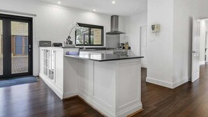 Una cocina moderna con armarios blancos, una isla central y un amplio ventanal.