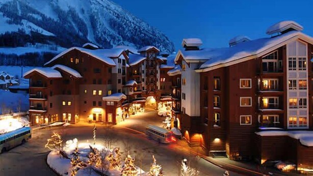 A snow-covered lodge with multiple buildings, a central courtyard, and a mountain in the background. - Mountaineer Square 313 | 1BR Walk-to-Lifts Condo, Sleeps 4, Pool & Hot Tub (Crested Butte)