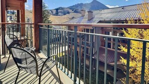 A balcony with a view of a mountain and a building with a metal roof. - Mountaineer Square 313 | 1BR Walk-to-Lifts Condo, Sleeps 4, Pool & Hot Tub (Crested Butte)