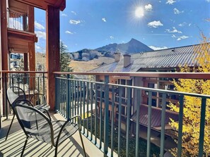 A balcony with a view of a mountain and a building with a metal roof. - Mountaineer Square 313 | 1BR Walk-to-Lifts Condo, Sleeps 4, Pool & Hot Tub (Crested Butte)