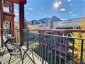 A balcony with a view of a mountain and a building with a metal roof. - Mountaineer Square 313 | 1BR Walk-to-Lifts Condo, Sleeps 4, Pool & Hot Tub (Crested Butte)