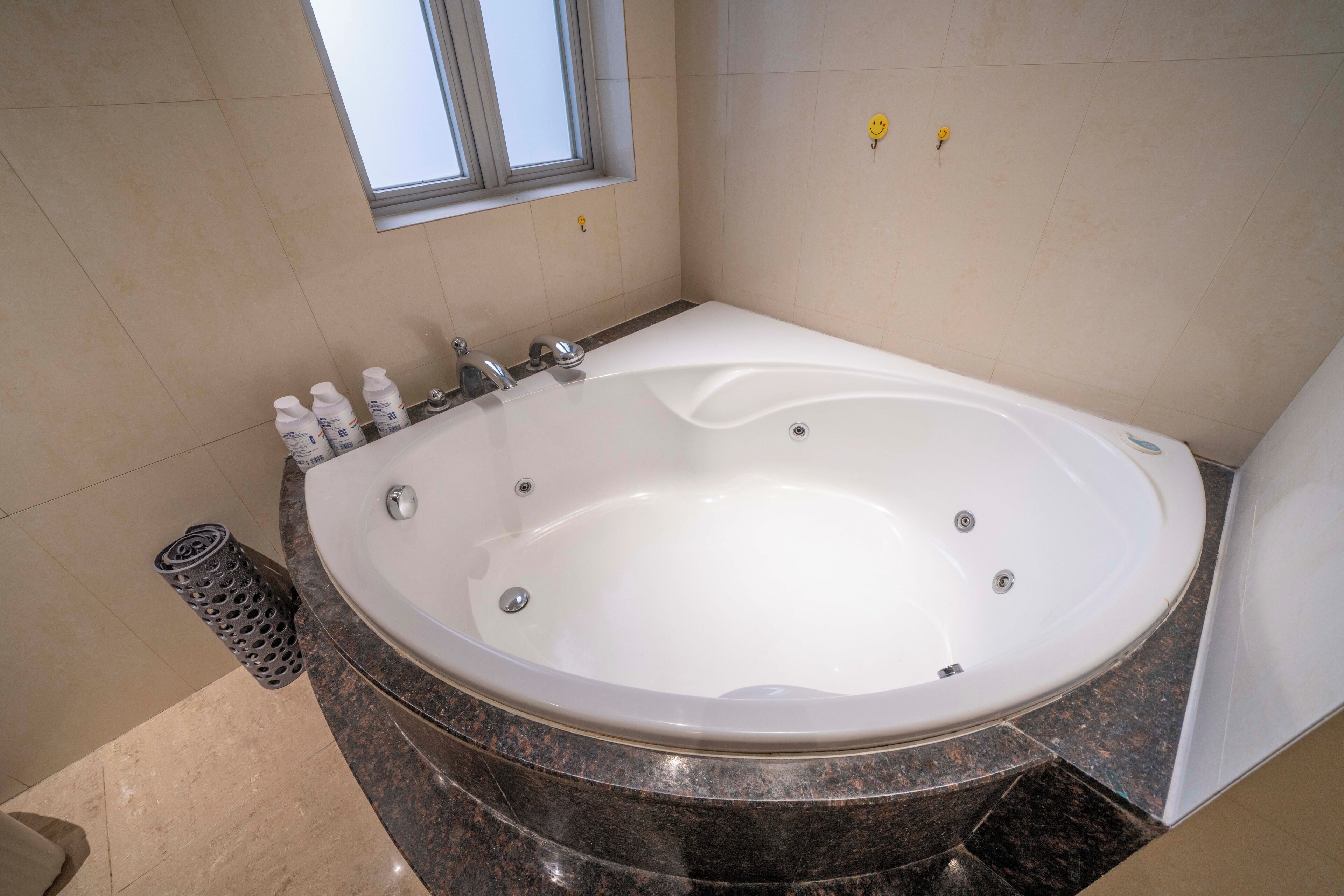 Un baño moderno con una bañera independiente grande, una ventana y piso de baldosas.