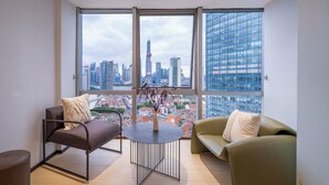 A modern living room with a large window offering a city view, a round table, and two sofas. - Book and Bed - North Bund (Shanghai)