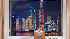 A room with a view of a city skyline at night, featuring illuminated buildings and a tower. - Book and Bed - North Bund (Shanghai)