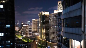 A nighttime cityscape with high-rise buildings, illuminated windows, and a crosswalk. - Book and Bed - North Bund (Shanghai)