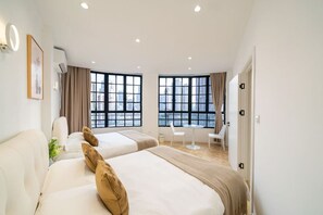 A hotel room with two beds, a desk, and large windows with city views. - Book and Bed - North Bund (Shanghai)